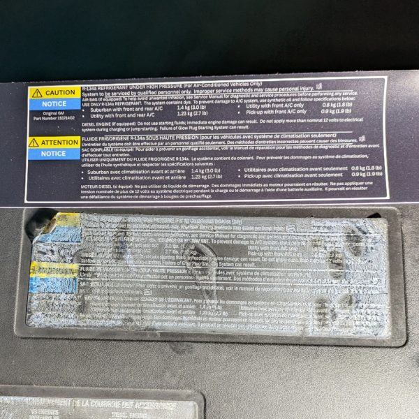 GMT800 AC refrigerant information label (R-134a)—new reproduction next to OEM decal on 2002 Chevrolet Tahoe shroud
